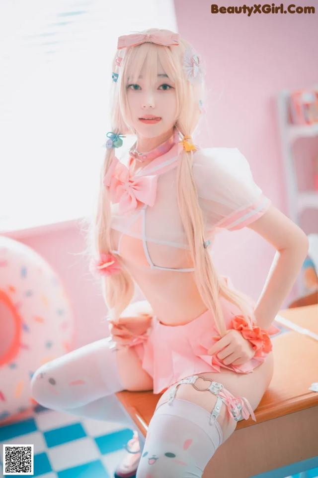 A woman in a pink and white outfit sitting on a table.