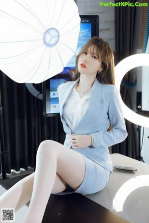 A woman sitting on top of a table next to an umbrella.