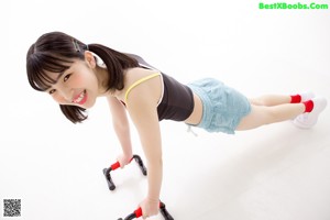 A young woman in shorts and a tank top holding a resistance band.