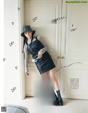 A woman in a black leather jacket and skirt posing for a magazine.