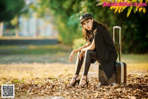 A woman in overalls and a hat is posing for a picture.