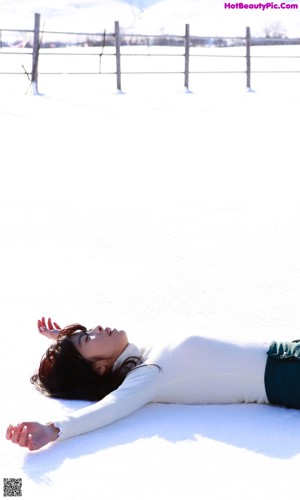 A woman in a white sweater and fur ear muffs praying.