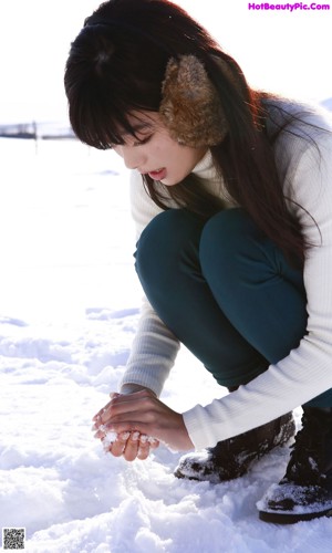 A woman is standing in the snow with her feet in the air.