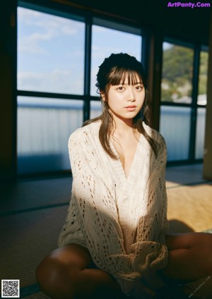 A woman in a white bikini sitting on a tatami mat.