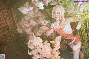 A woman sitting on a bench in front of a bunch of flowers.