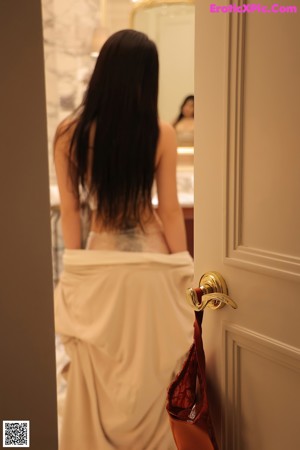 A woman in lingerie leaning against a door.