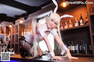 A woman in bunny ears sitting at a bar holding a wine glass.