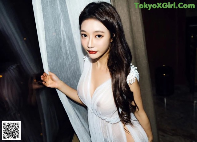 A woman in a white dress posing for a picture.