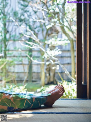 A woman in a kimono sitting on the floor reading a book.