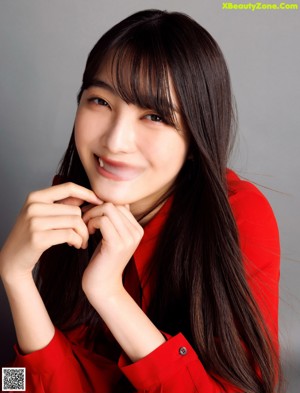 A woman in a red shirt is posing for a magazine.