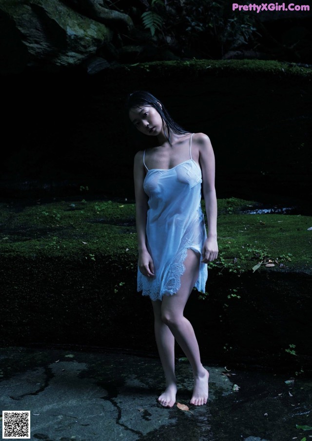 A woman in a white dress standing in the water.