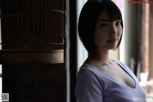 A naked asian woman standing in front of a window.