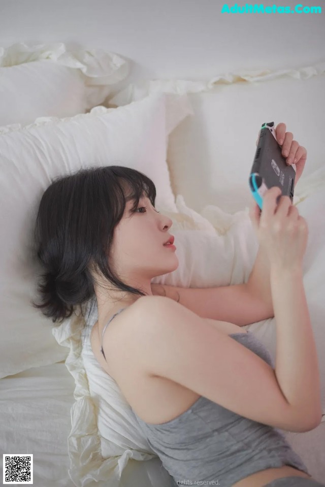 A woman laying on a bed holding a cell phone.