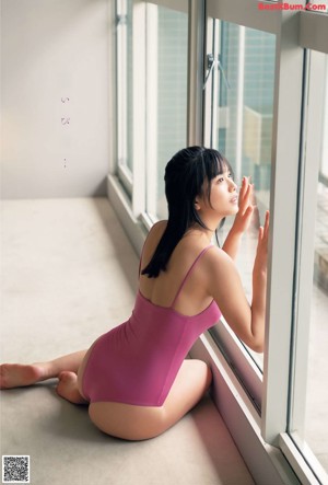 A woman laying on top of a bed next to a window.