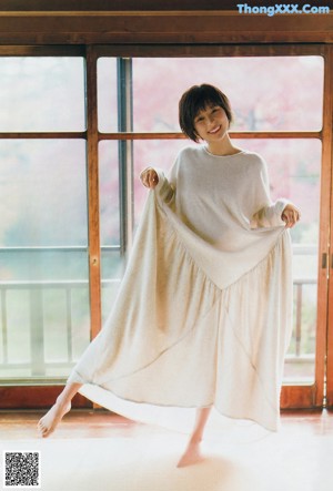 A woman in a white sweater posing for a magazine cover.