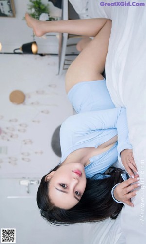 A woman in a blue bodysuit leaning against a window.