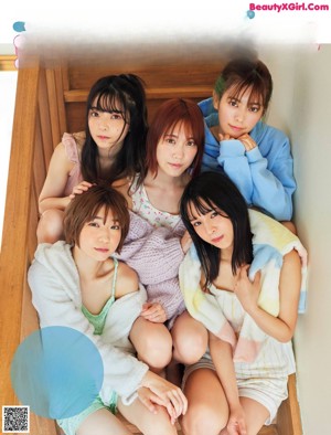 A group of young women sitting on top of a wooden staircase.