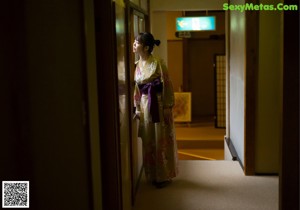 A woman in a kimono laying on the floor next to a window.