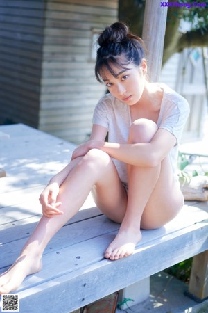 A woman in a blue tank top leaning on a railing.