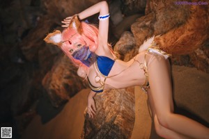 A woman in a bikini sitting on a log on the beach.