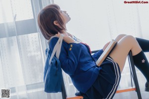 A woman in a school uniform sitting on a chair.