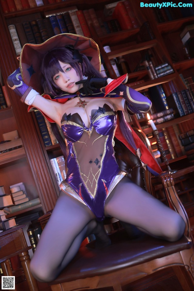 A woman in a purple outfit sitting on a chair in front of a bookcase.