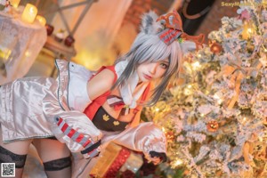 A woman in a red and white outfit posing in front of a Christmas tree.