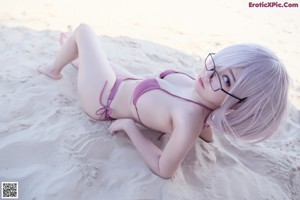 A woman in a bikini sitting on the beach.